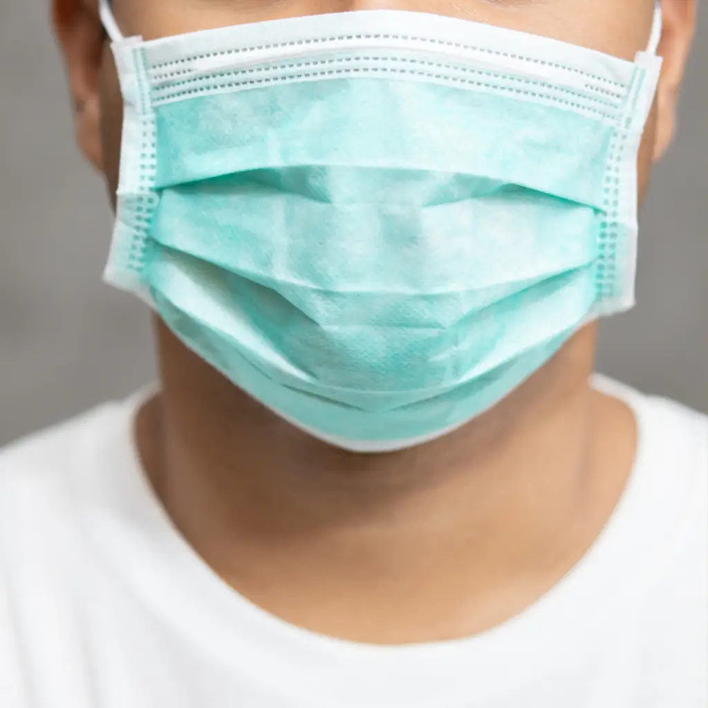 A man in a white t-shirt wearing a surgical mask showing how LevelUp teams follows COVID-19 protocols .