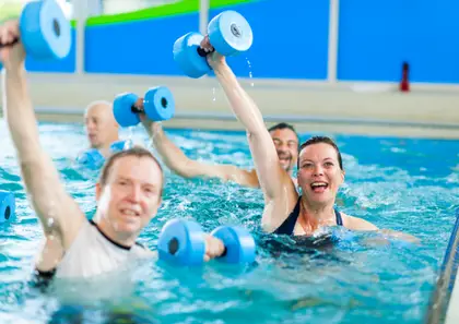 Group of people in a pool lifting weights underwater for LevelUp Aqua Therapy.